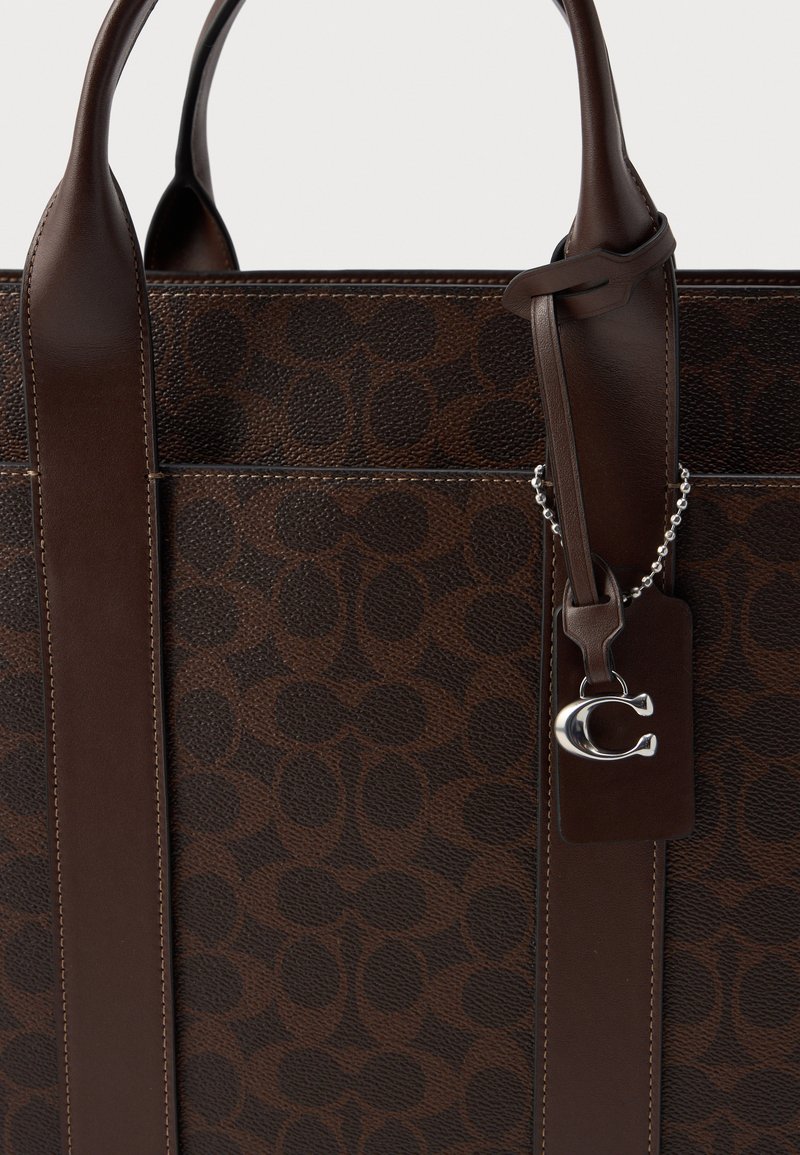 Tote in pelle marrone con superficie a motivo, texture liscia, doppi manici e un'etichetta metallica con un charm logo.