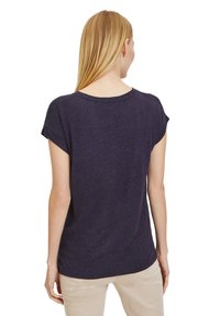 Námořnická modrá tričko s krátkým rukávem a kulatým výstřihem, nabízející volný střih a měkkou texturu. Pohled zád zobrazující minimální švy a žádné vzory.