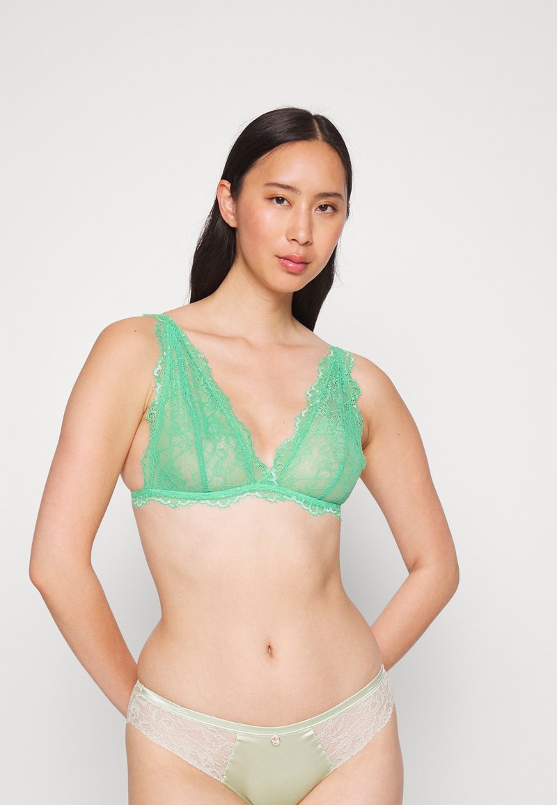 Bralette de renda em verde claro com um decote em V profundo e bordas em forma de onda; calcinhas em verde-menta combinando, com detalhes em renda e um pequeno detalhe decorativo.