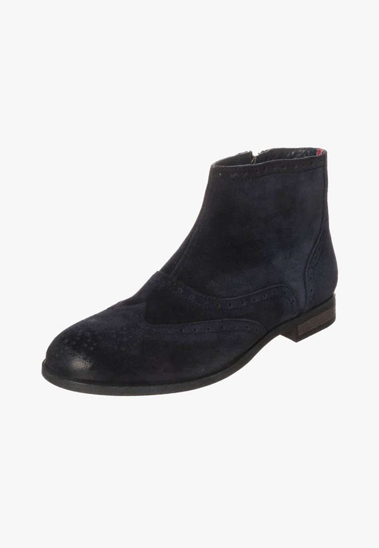 Bottines en daim bleu foncé avec un bout arrondi, des détails brogue et un petit talon. Comprend une fermeture éclair latérale pour un enfilage facile.