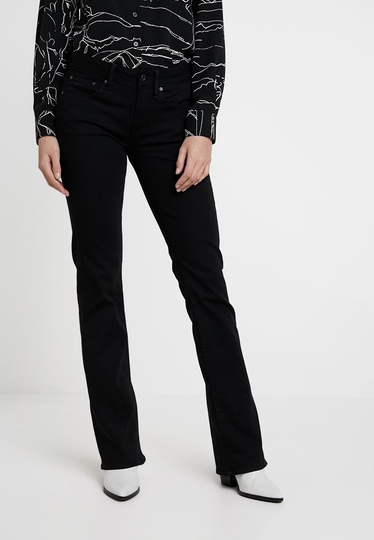 Jeans de mezclilla negros con un corte recto, que cuentan con cinco bolsillos y un ligero estiramiento. Llevados con una blusa de estampado en blanco y negro.