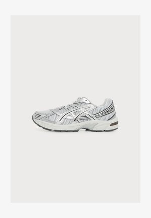 Chaussure de course athlétique argentée et blanche avec des panneaux en mesh et une semelle à motifs, vue de gauche sur fond blanc.