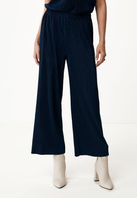 Marinblå vida byxor med ribbat mönster och elastiskt midjeband, matchat med beige ankelboots.