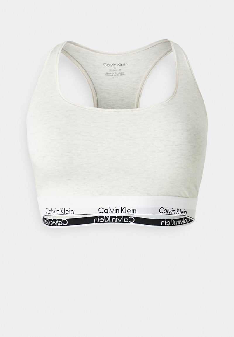 Lys grå sports-bh med rund hals og racerback-design. Har en svart og hvit Calvin Klein-logo band nederst.