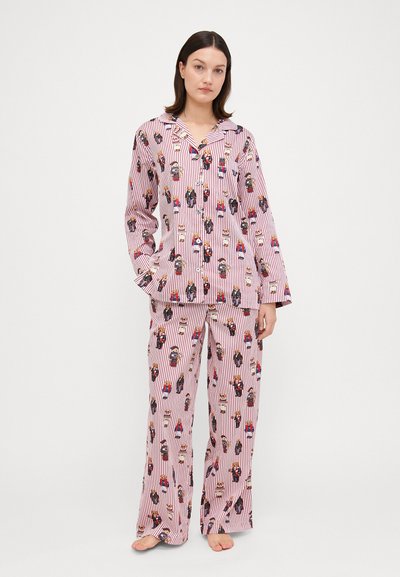 Long-sleeve pajama set in pink with red stripes and colorful nutcracker patterns. Loose-fitting, with a collared top and straight-leg pants.