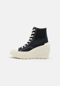 Hoge sneakers van zwart canvas met witte stiksels, met een chunky witte plateauzool en een klassiek vetersluiting ontwerp.