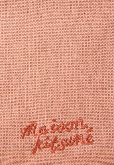 Tejido de color rosa con textura y apariencia de tejido, que presenta el logo bordado "maison kitsuné" en hilo naranja contrastante.