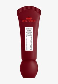 Tube en plastique rouge compressible avec une base arrondie, présentant une texture en relief sur le dessus. L'étiquette sur le côté comprend le nom du produit et des détails.