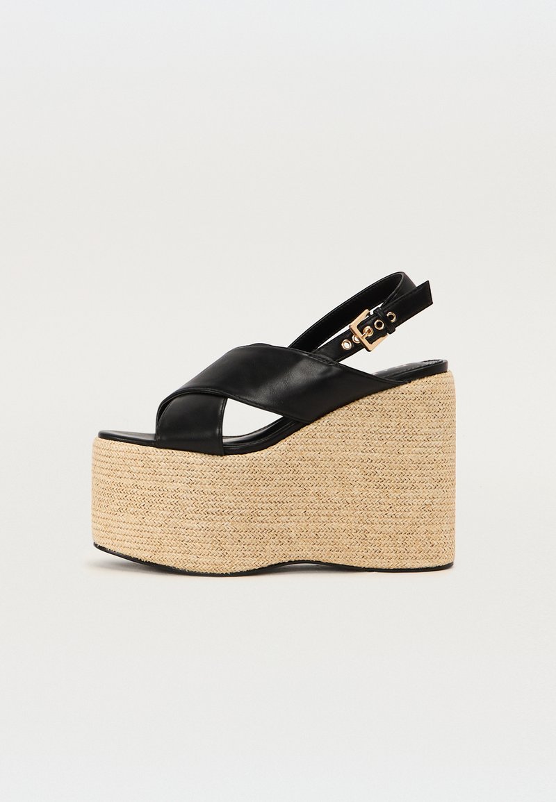 Sorte lærwedge-sandaler med en vevd jute plattform, med et kryssdesign på stroppene og en justerbar ankelstropp med et gullspenne.