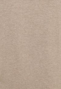 Beige stickad tyg med en fin, jämn textur och subtila horisontella och vertikala vävningsmönster.