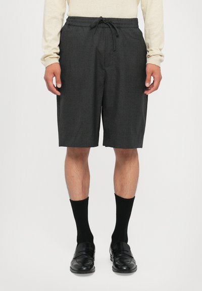 Grijze, op maat gemaakte shorts met een elastische tailleband en een trekkoord. Glad textuur, knielang, gecombineerd met zwarte sokken en instappers.