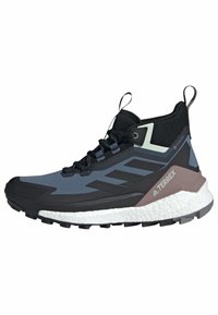 Chaussure de randonnée Adidas Terrex Gore-Tex noire et bleue avec semelle blanche coussinée et semelle extérieure robuste, vue de côté montrant les lacets et les languettes de tirage.