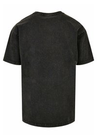 Camiseta de algodón negra con mangas cortas, cuello redondo y un corte ligeramente relajado. Presenta costuras visibles y una textura suave.