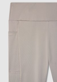 Beżowe legginsy o wysokim stanie wykonane z elastycznego materiału, z boczną kieszenią i płaskimi szwami zapewniającymi wygodę i trwałość.