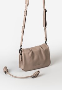 Borsa a tracolla in pelle beige con tracolla regolabile e manico annodato staccabile, esposta su uno sfondo bianco semplice.