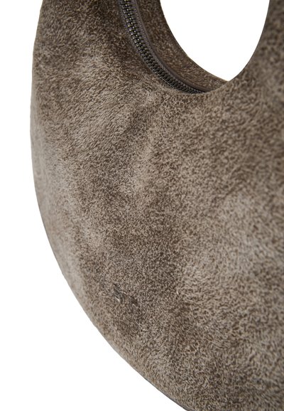 Cuscino in suede di forma ovale, con una superficie morbida e texturizzata di colore marrone. Una zip discreta è visibile, offrendo un dettaglio funzionale.
