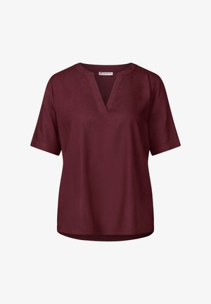 Blusa a maniche corte color bordeaux con scollo a V e tessuto morbido. Taglio dritto con un orlo posteriore leggermente più lungo.