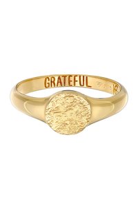 Guldring med ett texturerat, cirkulärt mittstycke. Inristat invändigt med orden "TACKSAM," med en slät ring. Fint hantverk i metall.