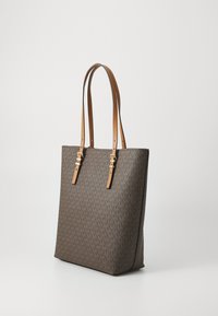 Sac fourre-tout en matériau marron à motifs avec deux poignées en cuir beige et des accessoires en métal doré, de forme rectangulaire avec un fond plat.
