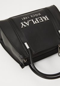 Zwarte nepleer handtas met zilveren logo "REPLAY SINCE 1981", gestructureerde vorm, bovenhandvaten en ritssluiting met metalen accenten.
