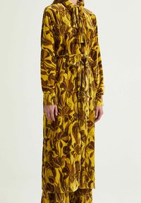 Abito lungo giallo con motivo floreale, colletto e cintura annodabile. Realizzato in tessuto morbido, con maniche lunghe e una vestibilità ampia.