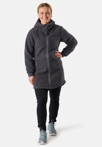 Grå fleece lång jacka med huva, med en frontdragkedja och sidofickor, kombinerad med svarta byxor och ljusblå skor.