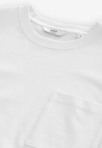 Hvid bomulds t-shirt med rund halsudskæring og en enkelt brystlomme. Stoffet har en blød tekstur og en afslappet pasform.