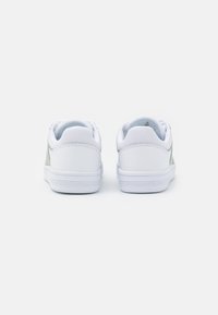 Sneakers bianchi con una texture liscia, colletto imbottito e accenti verdi. Suole in gomma con scanalature orizzontali per una migliore aderenza.