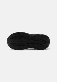 Semelle de sneaker noire avec un motif texturé comportant des rainures circulaires et allongées pour une traction et une adhérence. Fabriquée en matériau en caoutchouc.