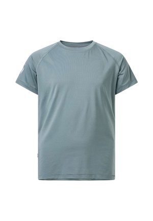 Jonge vrouw in sportkleding die een roze waterfles vasthoudt, draagt zwarte leggings, een grijs shirt en een zwart jasje dat om haar taille is gebonden.