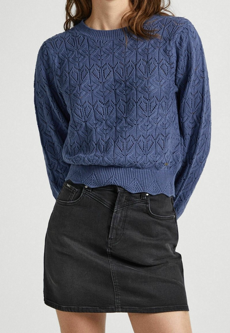Blauer gestrickter Pullover mit Blattmuster, Rundhalsausschnitt und geripptem Saum, kombiniert mit einem schwarzen Denim-Minirock mit Fronttaschen.