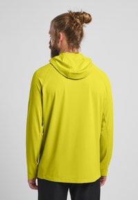 Maglietta a maniche lunghe con cappuccio in un vivace verde lime, realizzata in tessuto leggero e morbido, con cuciture rinforzate per una maggiore durata.