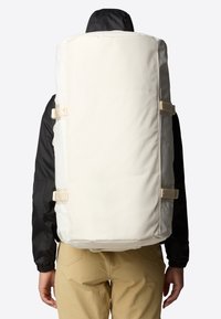 Large, cylindrical backpack in off-white fabric with beige straps. Features a smooth texture and minimalist design, suitable for outdoor use.