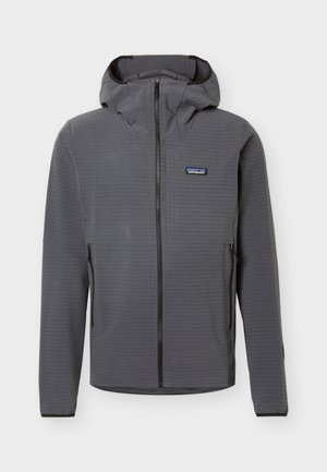 Veste à capuche grise à fermeture éclair intégrale avec deux poches latérales zippées et un petit logo Patagonia sur le côté gauche de la poitrine.