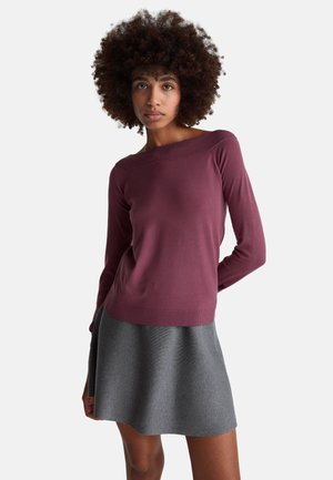 Jersey de manga larga color granate con un escote amplio. Combinado con una falda gris de línea A. Textura suave, silueta ajustada y detalles acanalados.