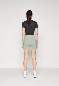Top corto nero e pantaloncini alta vita verde menta. Il top presenta un motivo testurizzato; i pantaloncini sono aderenti con un design elegante.