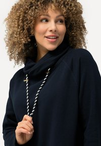 Marineblaue Sweatshirt mit einem Kapuzenkragen, weiß-grau gestreifter Kordel und goldfarbene Hardware-Accessoires. Weicher Stoff und lockere Passform.