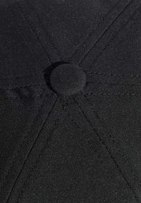 Black cap with a textured fabric, featuring a rounded top button, visible stitching, and a smooth surface. The interior shows fabric lining.