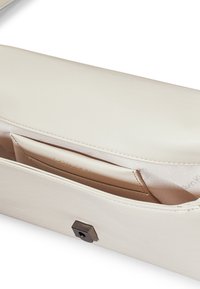 Borsa a mano in morbida pelle beige, con una consistenza liscia, una forma rettangolare e una chiusura esagonale scura. Include una fodera in tessuto color beige.