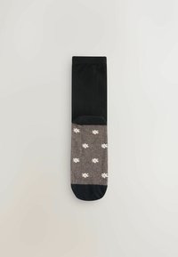 Zwarte en grijze sokken met een bloemenpatroon. Het grijze gedeelte heeft kleine witte bloemen, zwarte teen en boord. Zacht textielmateriaal.