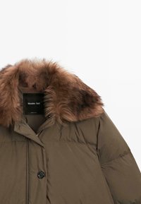 Brown padded winter coat with large fluffy fur collar and black button closure, partially zipped, showing inner brand label.