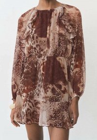 Robe animal print marron et crème avec des manches longues, un buste plissé, un col à volants et une jupe évasée. Tissu léger et texturé.