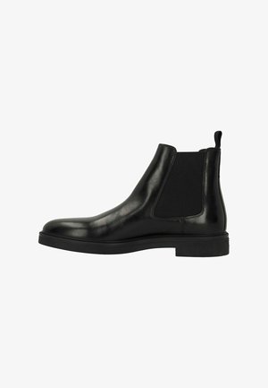 Botte Chelsea en cuir noir avec des panneaux élastiques sur les côtés, bout arrondi et semelle en caoutchouc plate. Dotée d'une bande de tirage à l'arrière pour un enfilage facile.