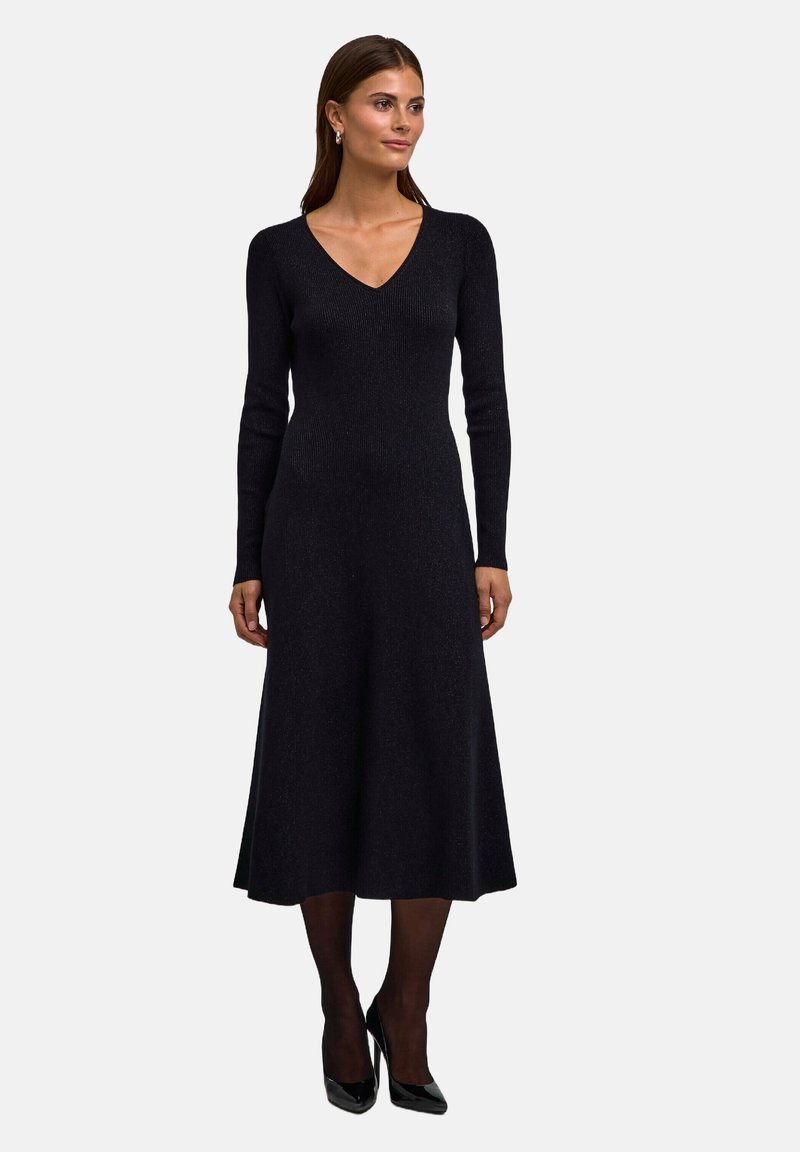 Abito nero in maglia con scollo a V, maniche lunghe e gonna a ruota. Realizzato in tessuto testurizzato che aggiunge un leggero luccichio.