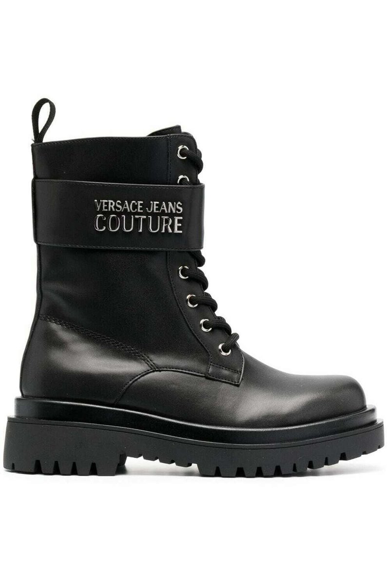 Botín de cuero negro hasta el tobillo con una suela gruesa, que presenta herrajes en plata y "VERSACE JEANS COUTURE" bordado en una correa alrededor de la parte superior.