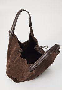 Bruine suède totebag met een zachte textuur, leren handvatten en een open top. Voorzien van binnenclips en een platte bodem voor stabiliteit.