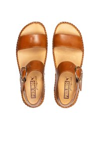 Sandalias de cuero marrón con dos correas anchas y una hebilla lateral. Costuras texturizadas a lo largo de los bordes. Plantilla suave con el logo.