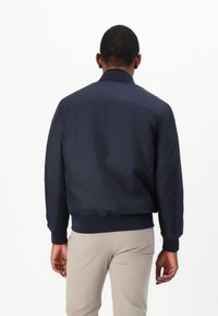 Marine bomberjakke med en jevn tekstur, ribbede mansjetter og liv. Designet med en klassisk krage og en avslappet passform.