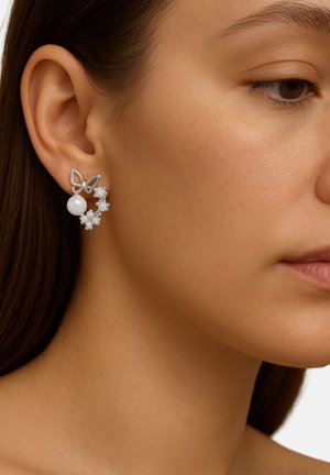 Silberne Schmetterlings-Ohrstecker mit einer zentralen weißen Perle und floralen Akzenten, die mit klaren Kristallen verziert sind und ein filigranes Design sowie eine besondere Textur zeigen.