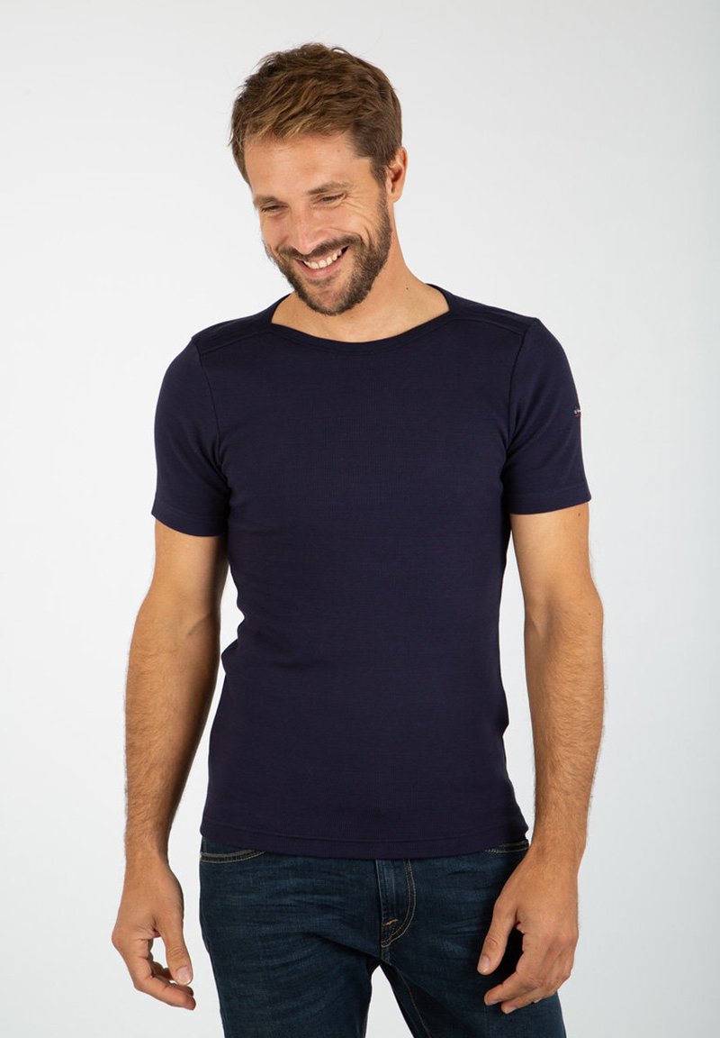 Maglietta blu navy a maniche corte realizzata in tessuto a coste. Presenta un collo arrotondato e cuciture delle spalle minimali, abbinata a jeans scuri.